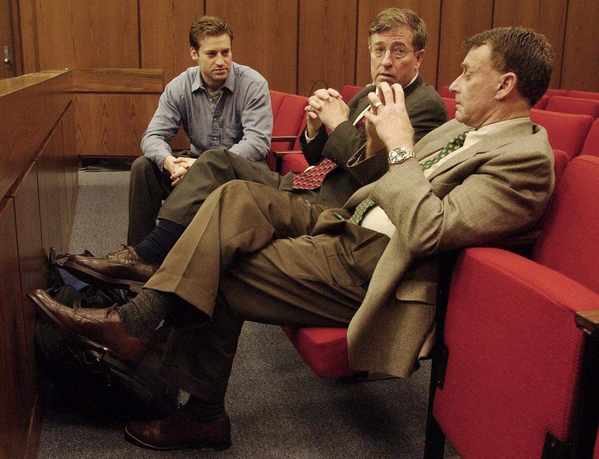Michael Peterson (right) speaks with brother Bill Peterson (center) and son Todd Peterson (left) before the start of court proceedings May 29, 2003.