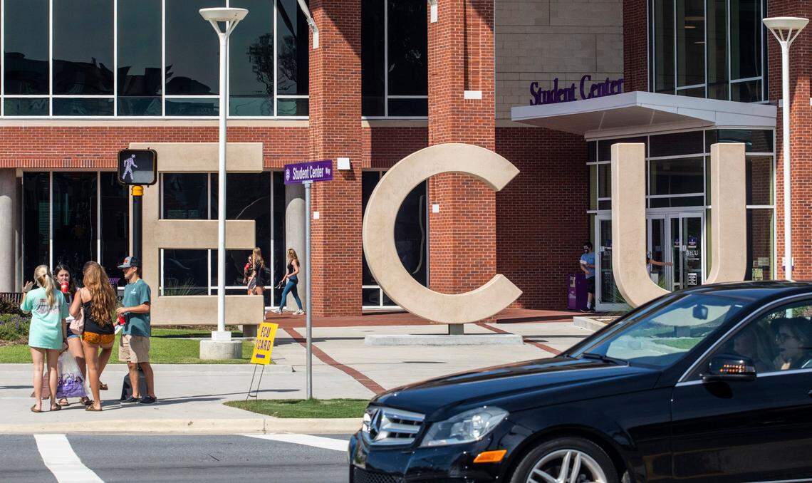 Students, not wearing masks, wait to cross 10th street Tuesday, August 18, 2020 outside the Student Center at East Carolina University.