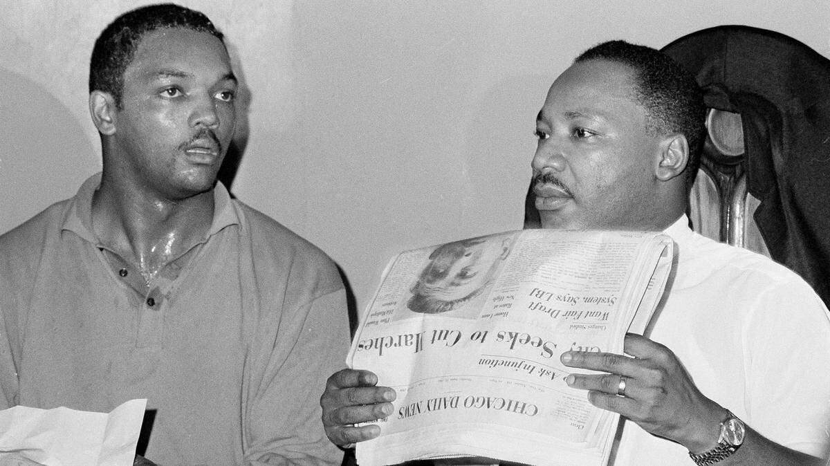 Civil rights leader Dr. Martin Luther King, Jr., right, and his aide Rev. Jesse Jackson are seen in Chicago, Aug. 19, 1966. Dr. King holds a Chicago Daily News paper with a headline that reads “City Seeks To Cut Marches.” During a meeting with 1,000 civil rights workers in a South Side church, King said, “We aren’t going to let any injunction turn us around.”