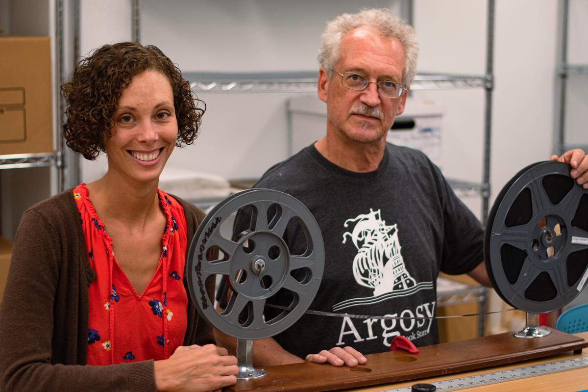 North Carolina Collection manager Lauren Menges (left) and local film historian Tom Whiteside (right) pose for a photo with the original 16mm negative print of “Negro Durham Marches On” at the Durham County Library on July 28, 2021.