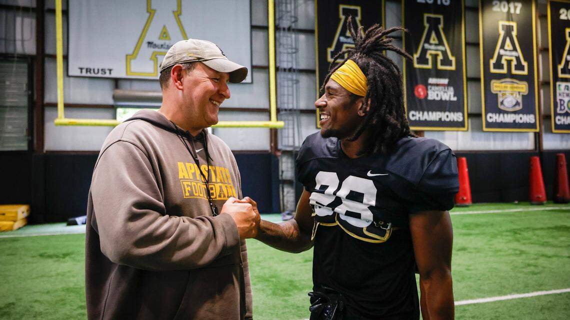 Appalachian State head football coach Shawn Clark jokes with outside linebacker Kesean Brown (28) during an indoor practice in Boone, N.C., Tuesday, Aug. 30, 2022. The Appalachian State Mountaineers football team is preparing to host UNC this weekend.