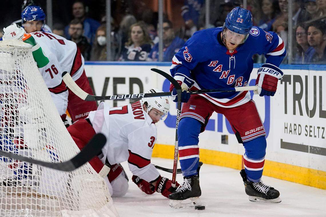 New York Rangers defenseman Adam Fox (23) clears the puck from Carolina Hurricanes right wing Andrei Svechnikov (37) from behind the net in the first period of Game 4 of an NHL hockey Stanley Cup second-round playoff series, Tuesday, May 24, 2022, in New York. (AP Photo/John Minchillo)