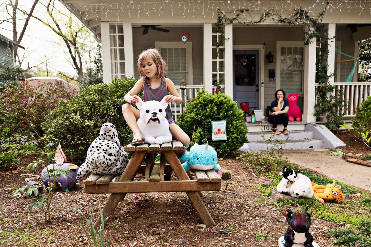 Lilabett Kerr, 6, shows off one of her cherished animals during a neighborhood animal safari as her mom, Casie Kerr, watches from the porch on Friday, March 27, 2020. Several homes in the Boylan Heights neighborhood in Raleigh placed animals around in their yards for others to discover.