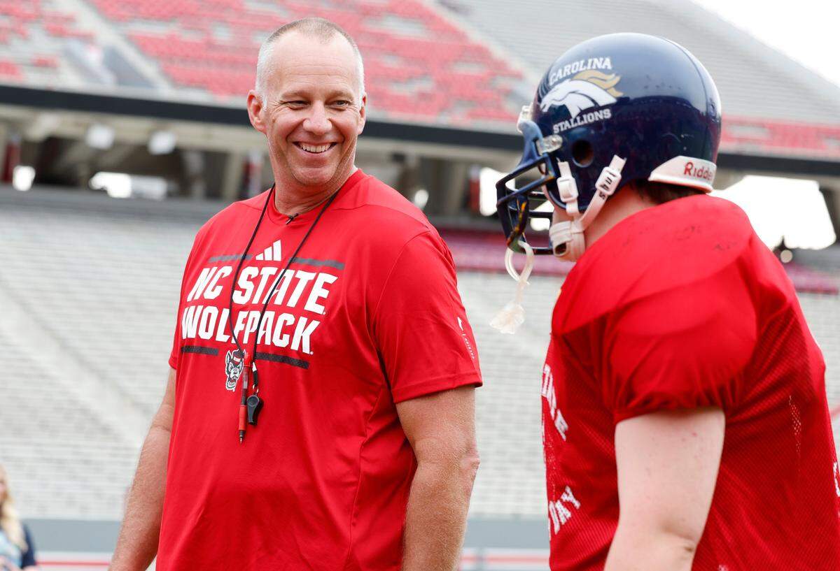 N.C. State head football coach Dave Doeren laughs as he talks with Sam Hening during Victory Day at Carter-Finley Stadium in Raleigh, N.C., Friday, August 2, 2024.