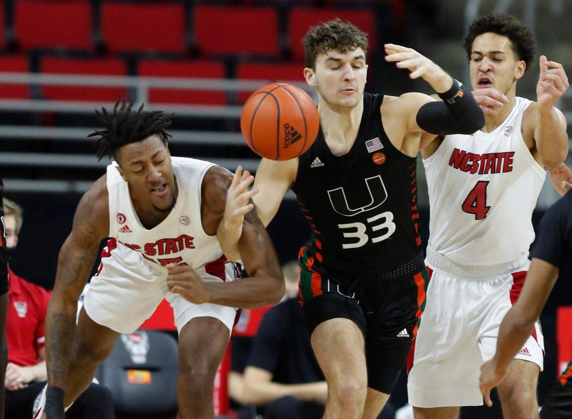 N.C. State’s Manny Bates (15), Jericole Hellems (4) and Miami’s Matt Cross (33) fight for a rebound during the first half of N.C. State’s game against Miami at PNC Arena in Raleigh, N.C., Saturday, January 9, 2021.