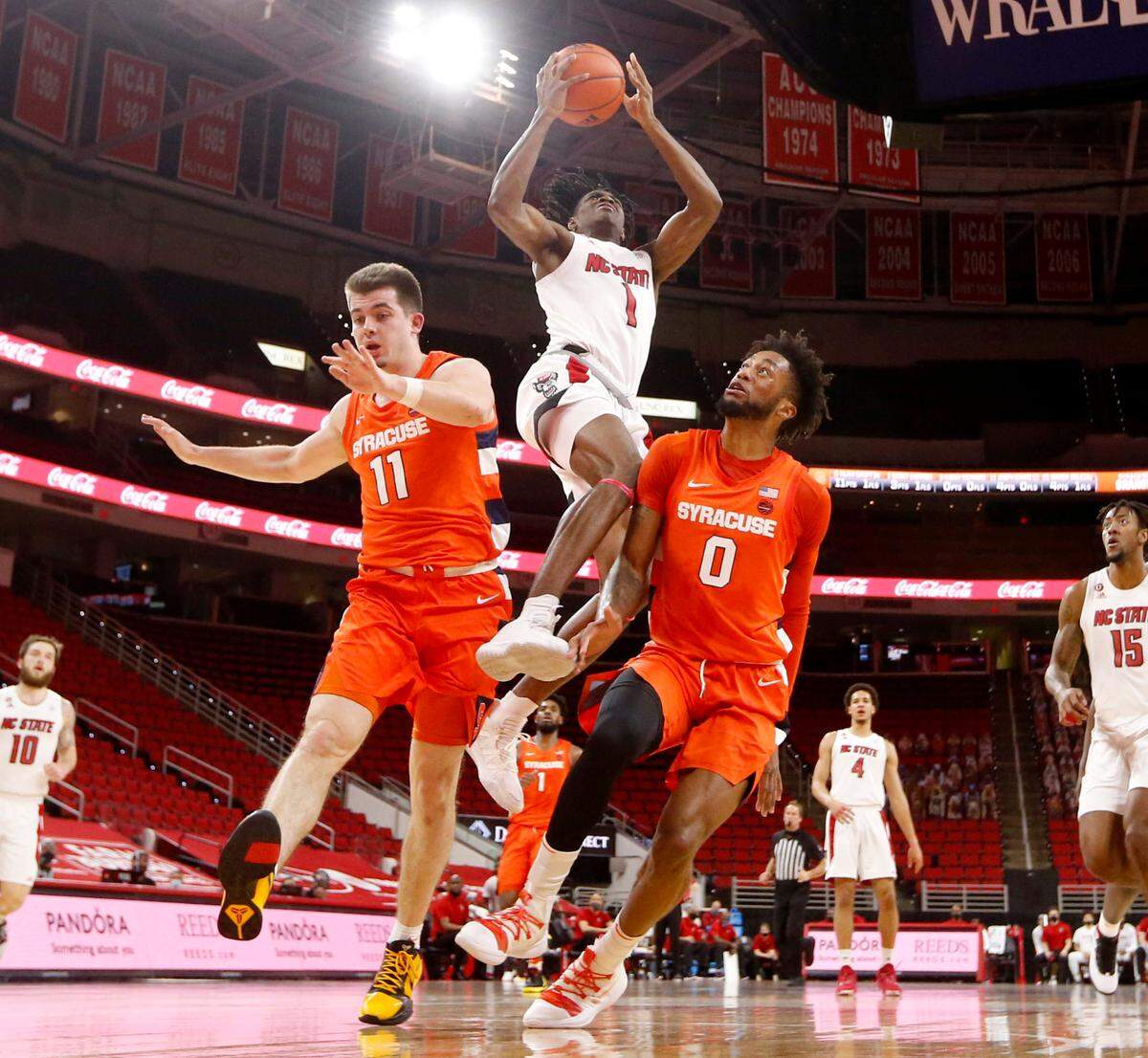 N.C. State’s Dereon Seabron (1) is fouled as he goes up towards the basket between Syracuse’s Joseph Girard III (11) and Alan Griffin (0) during Syracuse’s 77-68 victory over N.C. State at PNC Arena in Raleigh, N.C., Tuesday, February 9, 2021.