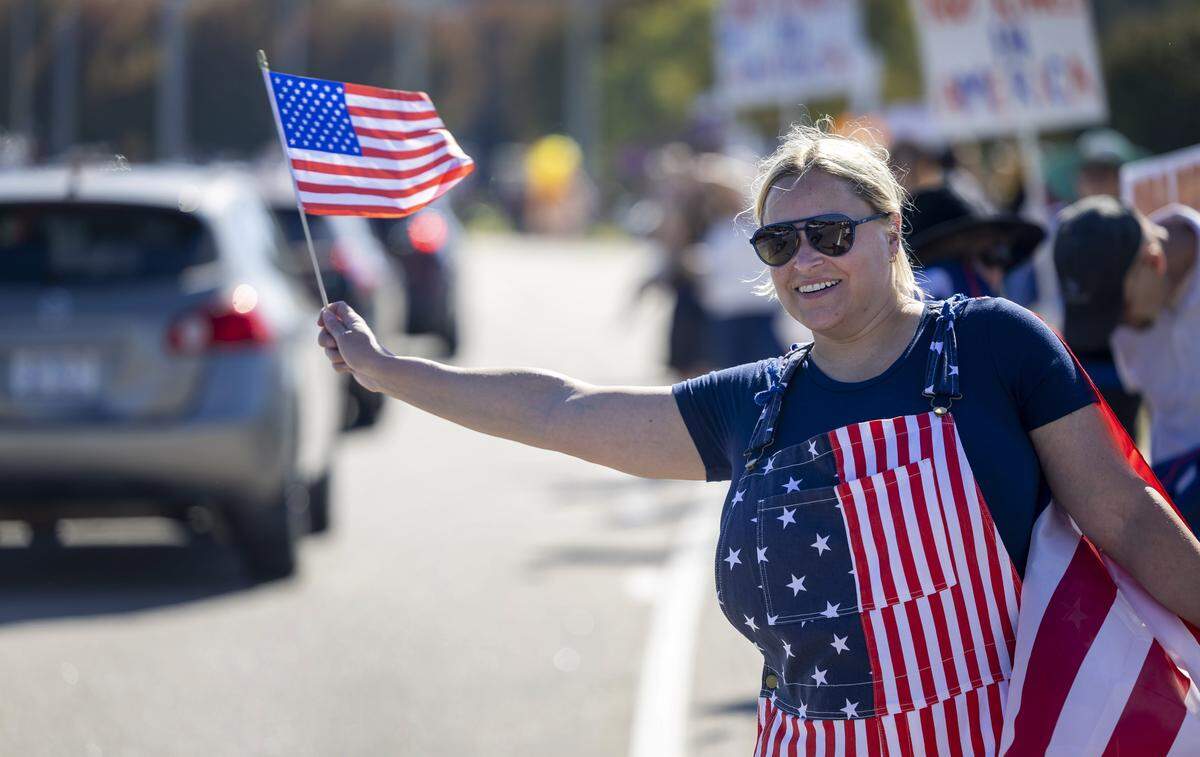 Adrian Raley, of Raleigh, N.C.waves her flag at passing motorists during the ‘No Kings’ demonstration along Capital Blvd. on Saturday, October 18, 2025 in Raleigh, N.C. 