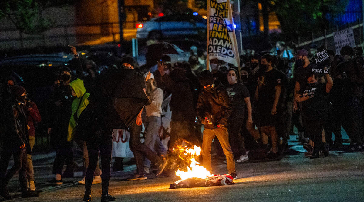 Demonstrators light a flag on fire in downtown Raleigh during a march following a vigil for Daunte Wright and others killed by police Sunday, April 18, 2021.