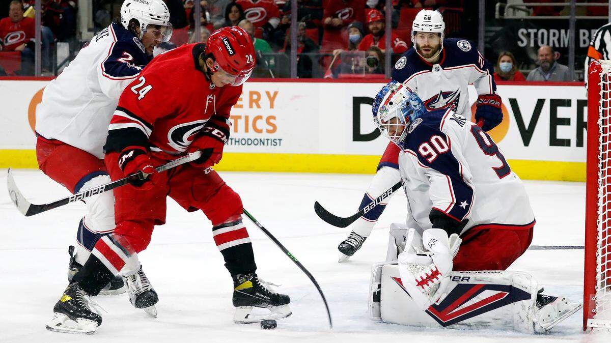 Carolina Hurricanes’ Seth Jarvis (24) tries to control the puck in front of Columbus Blue Jackets goaltender Elvis Merzlikins (90) with Blue Jackets’ Andrew Peeke (2) and Oliver Bjorkstrand (28) nearby during the second period of an NHL hockey game in Raleigh, N.C., Thursday, Jan. 13, 2022. (AP Photo/Karl B DeBlaker)
