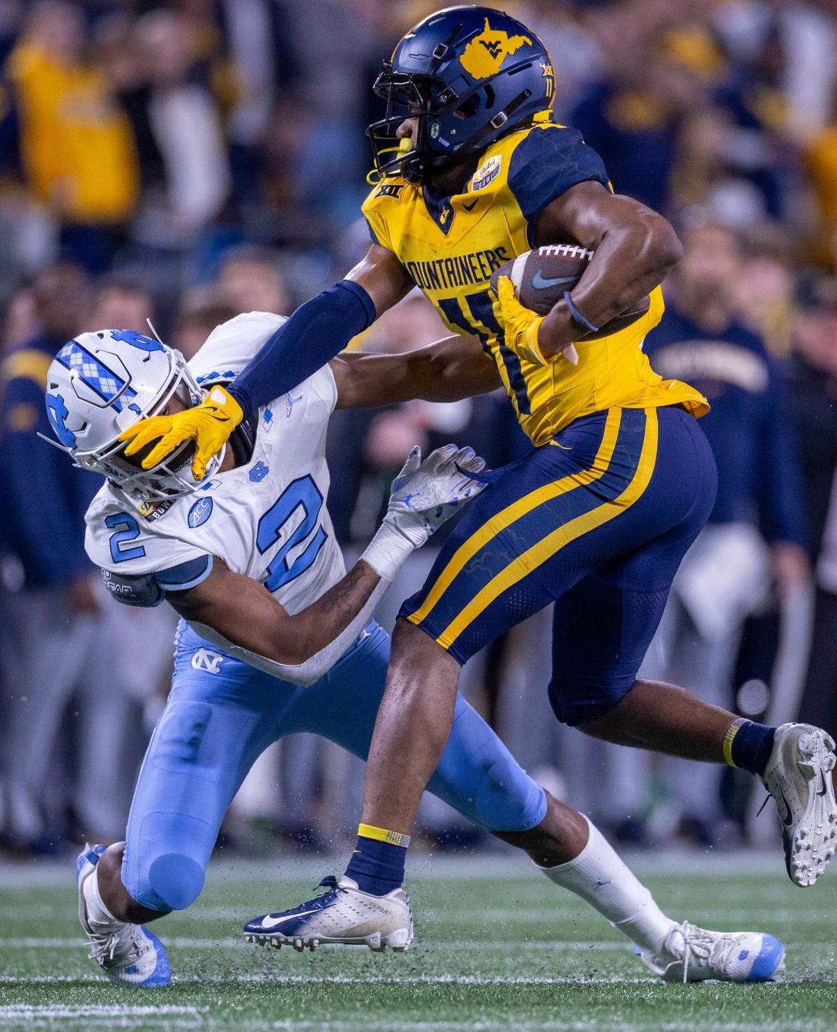 North Carolina’s Don Chapman (2) works to stop West Virginia’s Beanie Bishop Jr. (11) on a punt return in the fourth quarter during the Duke’s Mayo Bowl on Wednesday, December 27, 2023 at Bank of American Stadium in Charlotte, N.C.