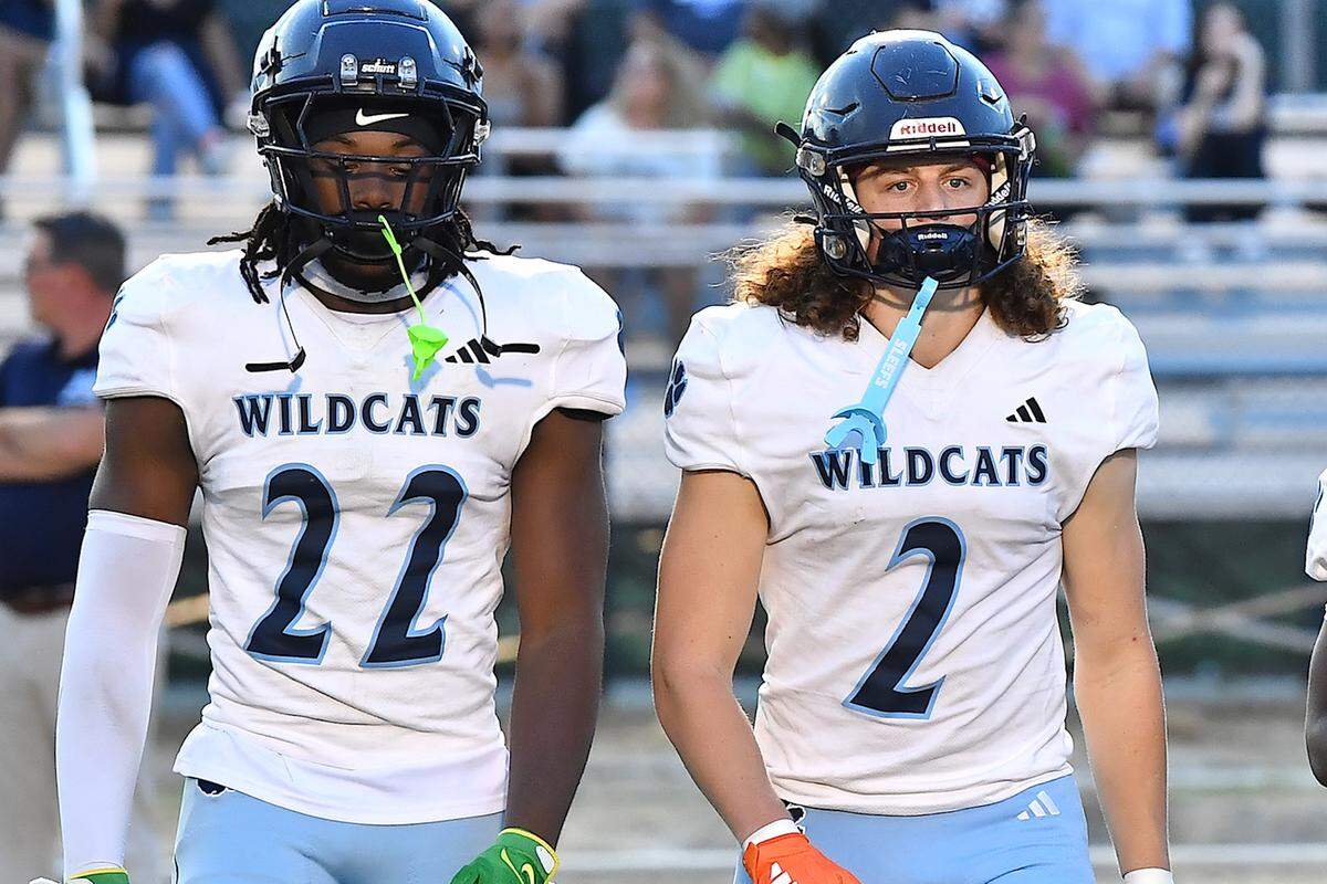 Millbrook captains Rashad Streets (22) and Quentin Cypher (2) march to the center of the field for the coin toss with Rolesville before the start of their game.