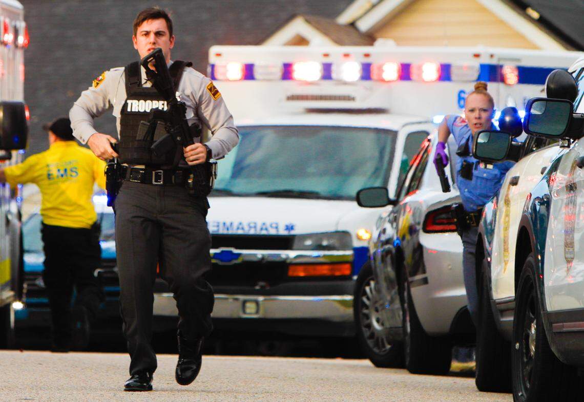 A Highway Patrol trooper (left) and Raleigh Police officer provide security around EMS vehicles at the scene of a mass shooting in the Hedingham neighborhood, Thursday afternoon, Oct. 13, 2022.