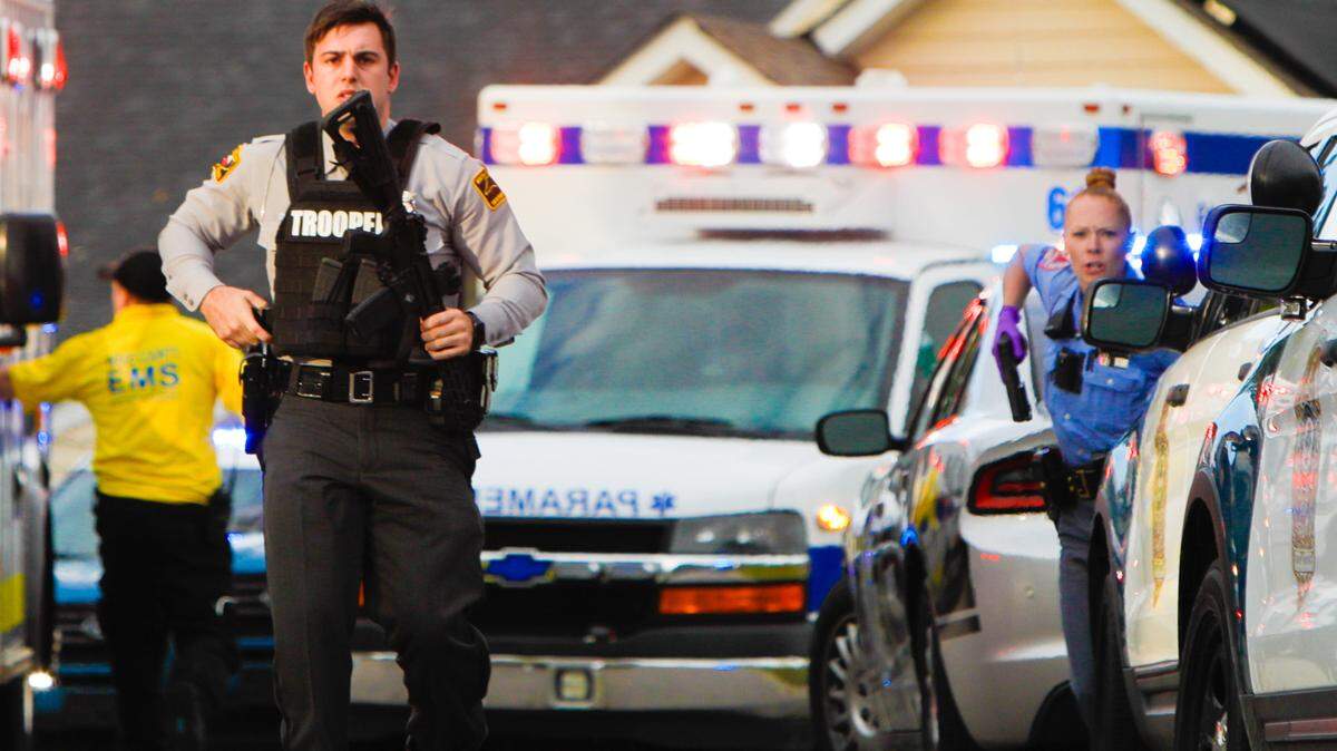A Highway Patrol trooper (left) and Raleigh Police officer provide security around EMS vehicles at the scene of a mass shooting Oct. 13, 2022 in the Hedingham neighborhood in Raleigh.