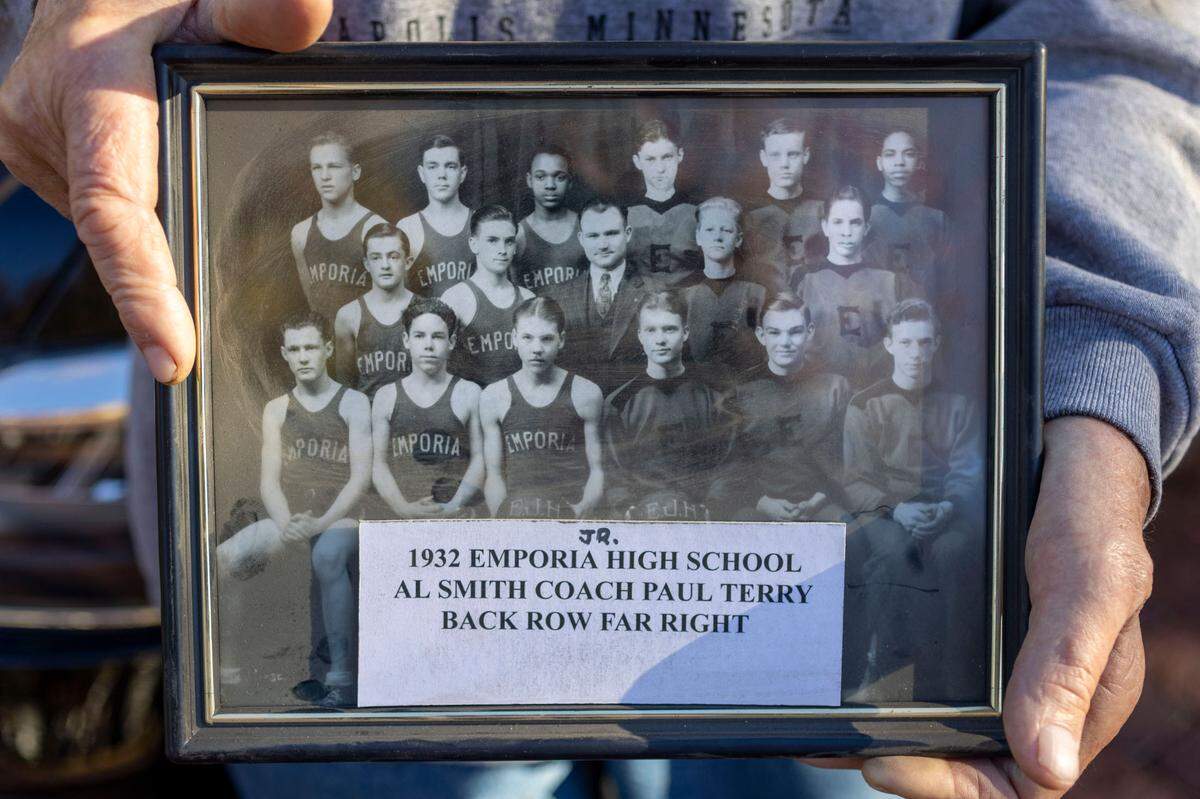 Ron Slaymaker, holds a framed photograph of the 1932 Emporia Jr. High basketball team, with head coach Alfred Smith, Dean’s Smith’s father. 