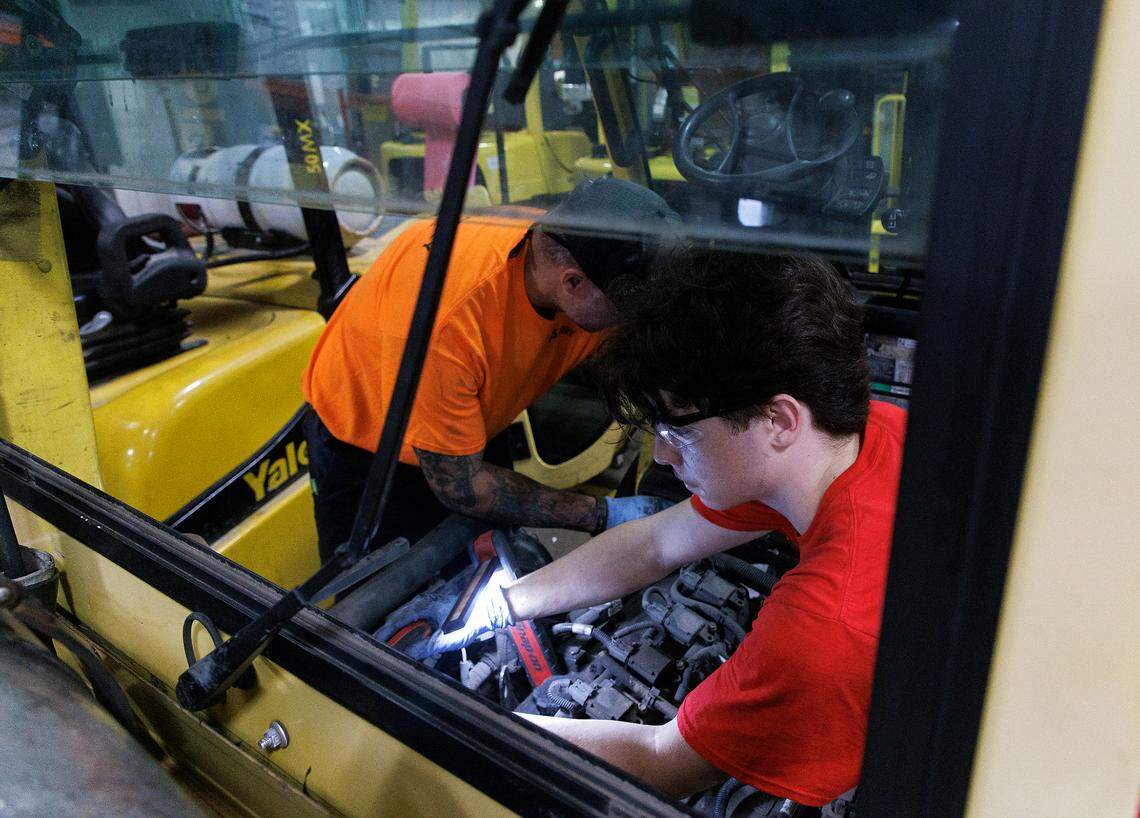 A Wake Technical Community College student works alongside senior shop technician Joe Weimer to replace parts of a forklift in the shop at The Gregory Poole Equipment Company in Raleigh, N.C. on Thursday, July 18, 2024.