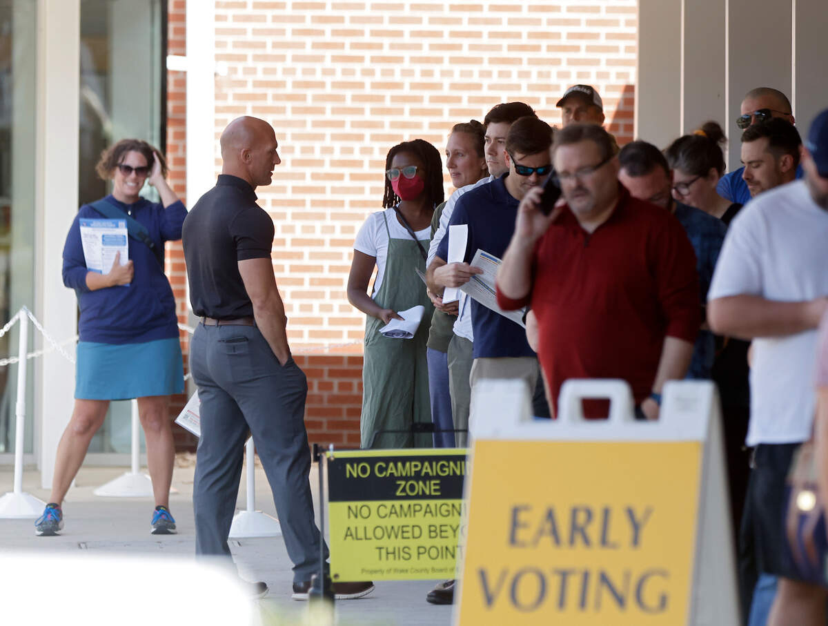 Steve Bergstrom, candidate for Wake County School Board, talks with people standing in line outside an early voting site in Holly Springs, N.C. on Friday, Nov. 4, 2022.