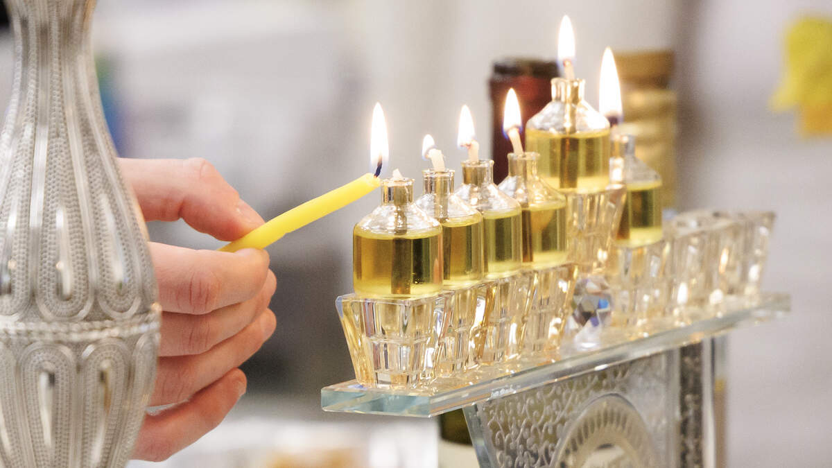 Zeevik Richie lights a menorah during an event hosted by Chabad of Durham-Chapel Hill at Skin Analytics at The Streets at Southpoint on Thursday in Durham. 