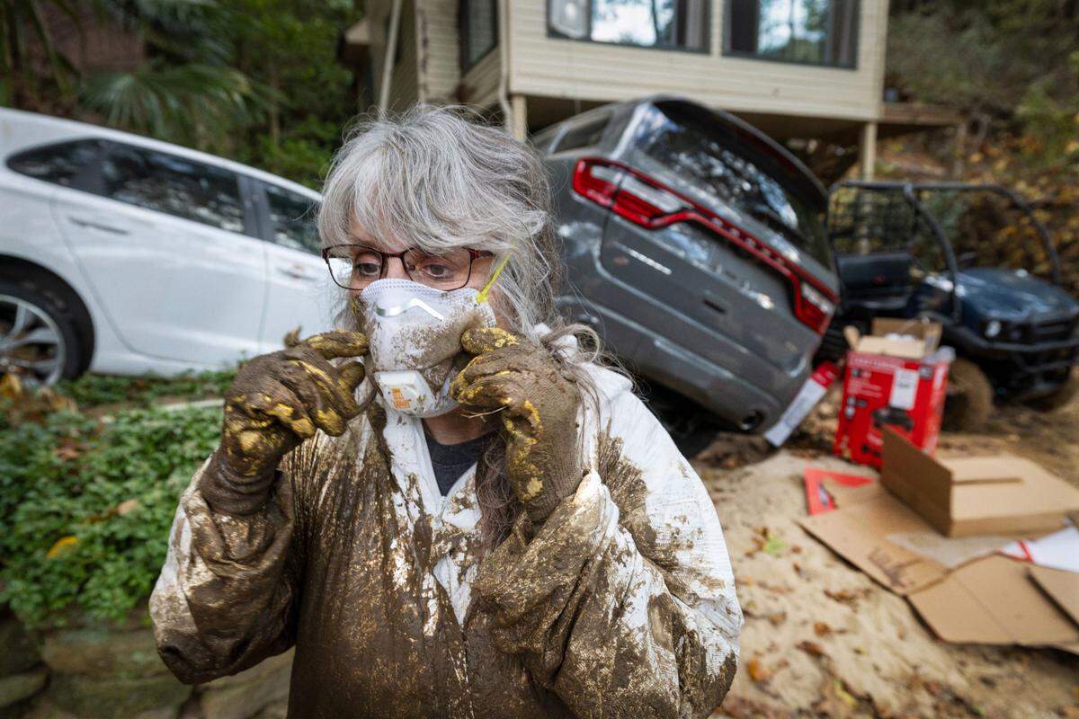 Susan Figetakis adjusts her protective mask as she works to clean out her home, flooded by the Green River during Hurricane Helene, on Oct. 7, 2024, near Saluda.