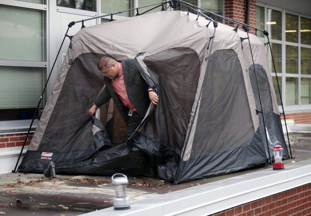 Conn Magnet Elementary school principal Gary Duvall exits his tent atop the first floor roof of the school after school Thursday, November 19, 2015 after stowing his gear where he will be staying the night Thursday into Friday morning classes after he promised to camp out on the school roof if the community raised $30 thousand in October to go toward a new school playground. He is lucky because he dodged Thursday morning’s rain.