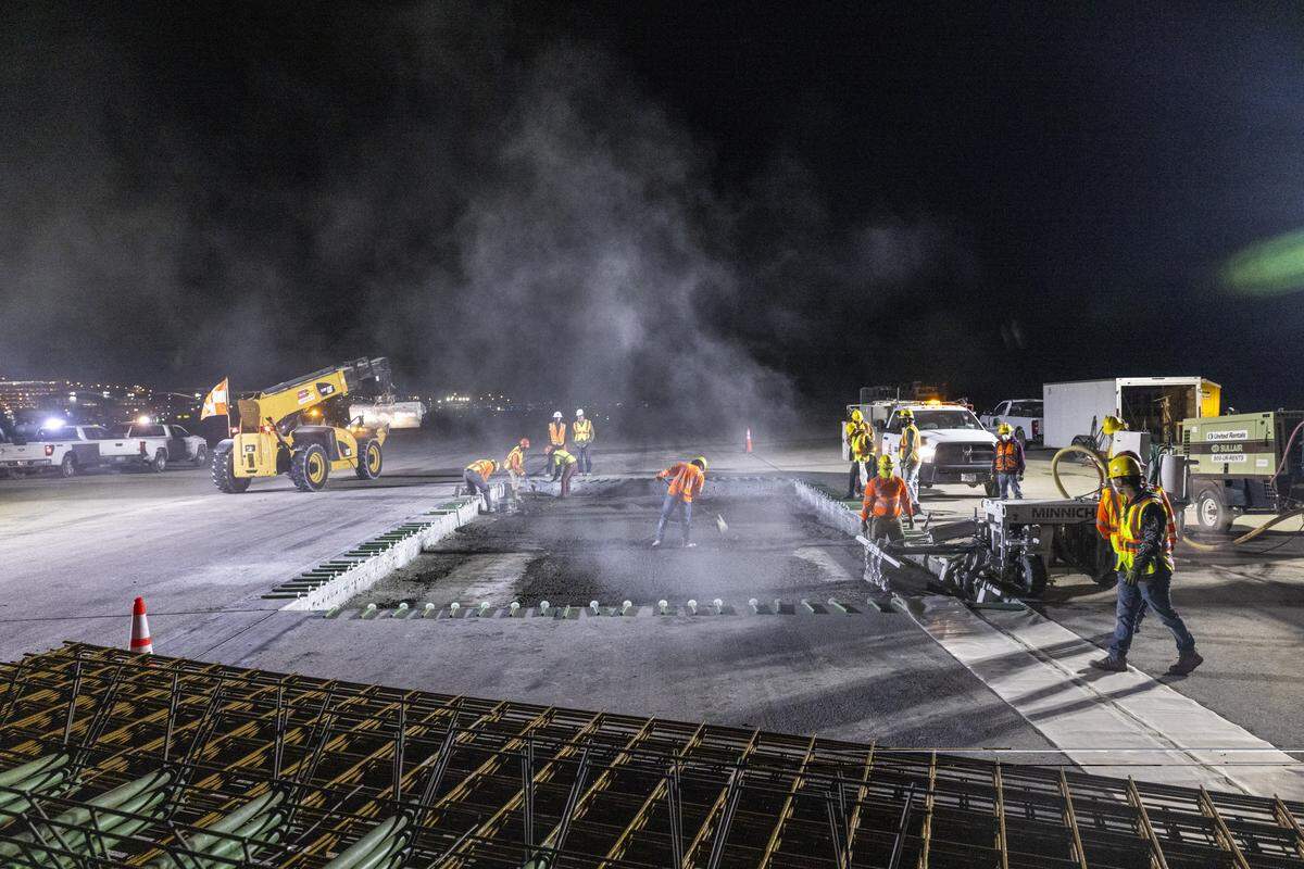 A drilling machine, right, makes holes in the side of the concrete walls surrounding the hole Hi-Way Paving has made in runway 5L/23R, the main runway at Raleigh-Durham International Airport, on Monday, Oct. 20, 2025. The steel rods placed around the hole will be inserted into the holes before new concrete is poured.