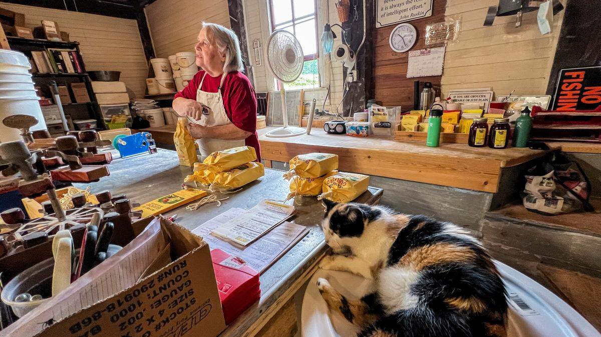 Miller Annie Perdue bags ground grain as her cat Millie sleeps nearby at the Old Mill of Guilford, built in 1767.