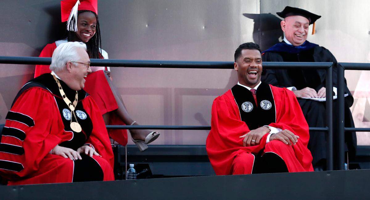 Chancellor Randy Woodson, left, and keynote speaker Russell Wilson laugh during N.C. State’s commencement ceremonies for the class of 2021 at Carter-Finley Stadium in Raleigh, N.C., Friday, May 14, 2021.
