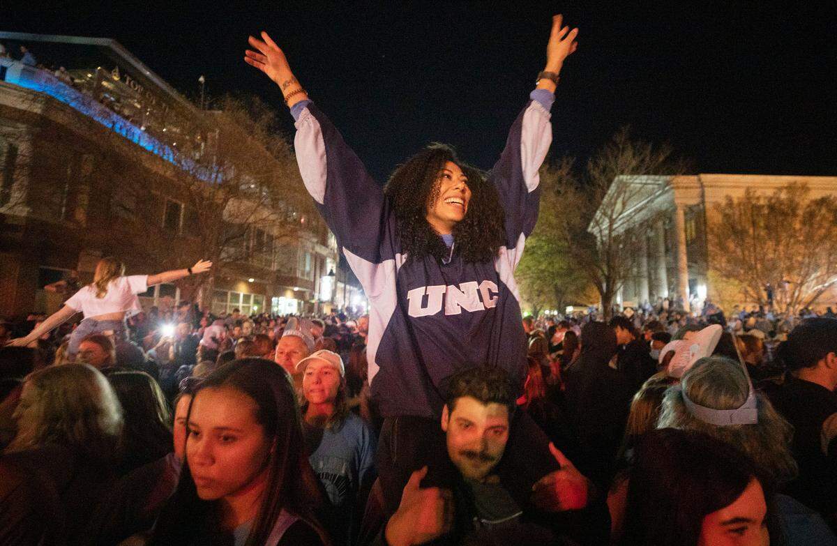 Amiah Matthews sits on the shoulders of Derek Polzer at the intersection of Franklin and Columbia Streets in Chapel Hill, N.C. as they celebrate UNC’s historic win over the Duke Blue Devils in the Final Four on Saturday, April 2, 2022.