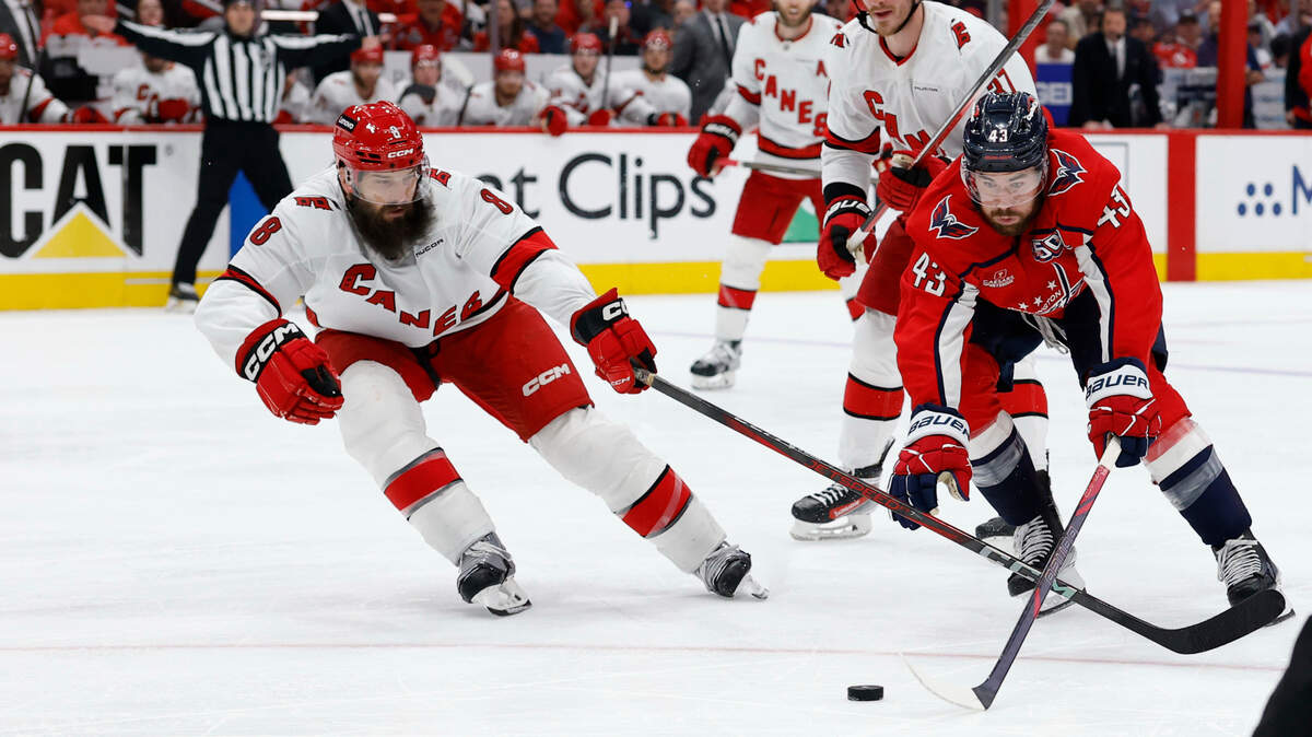 May 15, 2025; Washington, District of Columbia, USA; Washington Capitals right wing Tom Wilson (43) reaches for the puck as Carolina Hurricanes defenseman Brent Burns (8) defends in the third period in game five of the second round of the 2025 Stanley Cup Playoffs at Capital One Arena. Mandatory Credit: Geoff Burke-Imagn Images