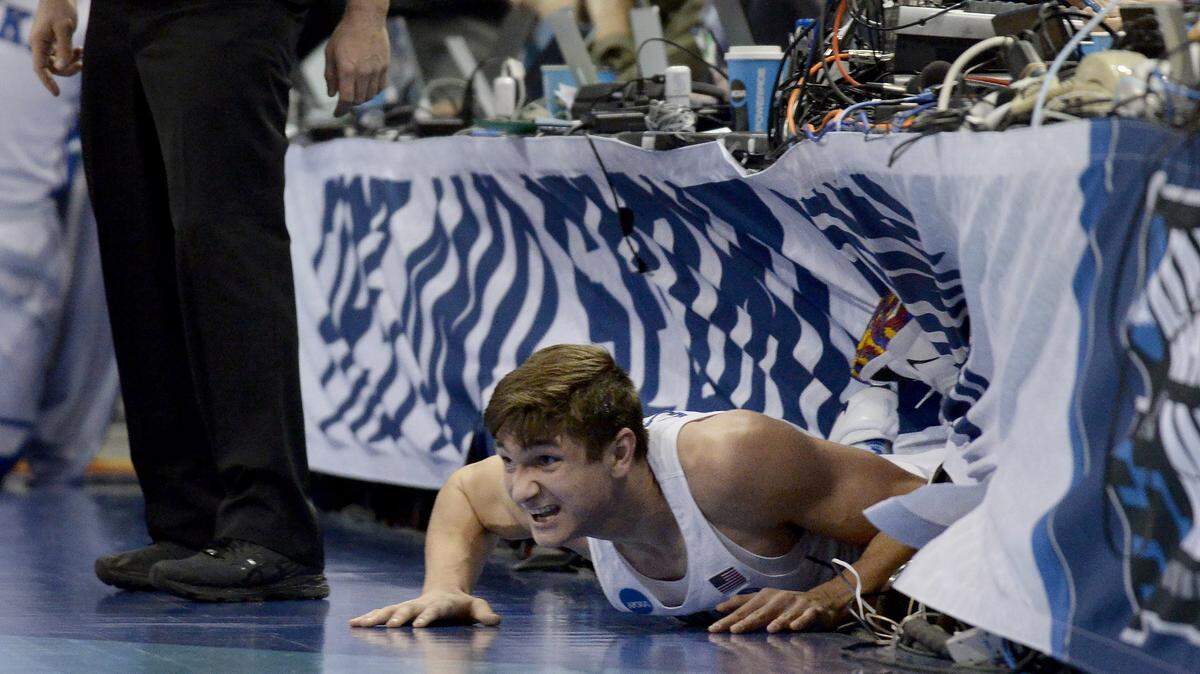 Duke guard Grayson Allen (3) crawls out from under the media table after saving a loose ball and flying out of bounds against Rhode Island.
