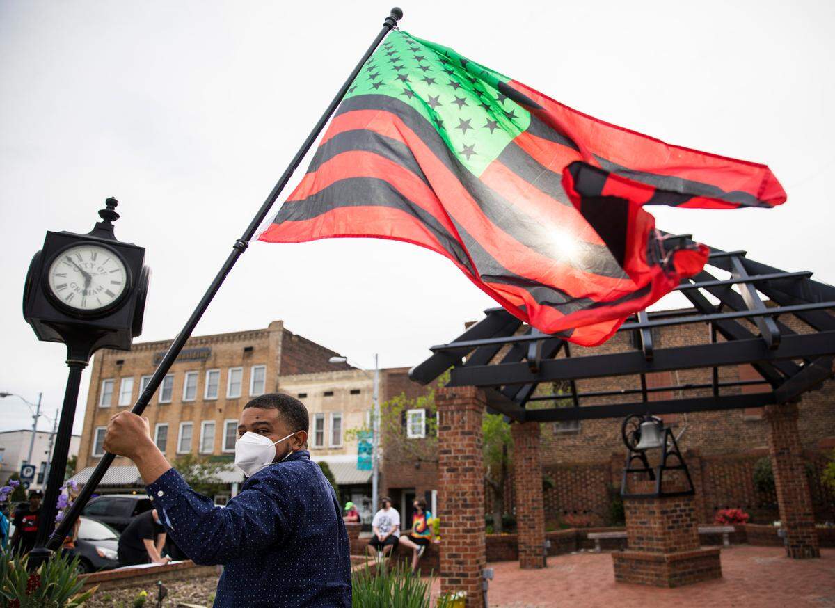 Maurice Wells waves a flag during an Occupy Graham demonstration in downtown Graham on April 14, 2021.