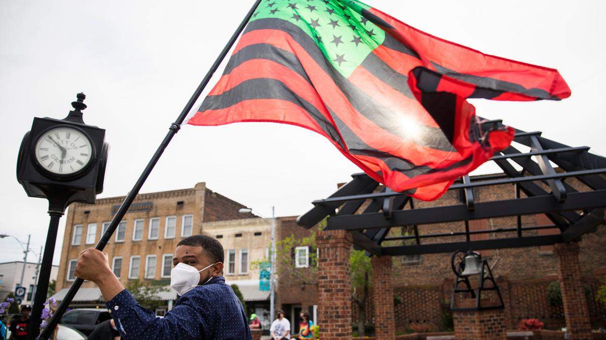 Maurice Wells waves a flag during an Occupy Graham demonstration in downtown Graham, N.C., on April 14, 2021.