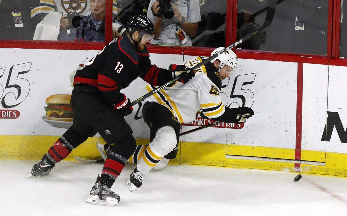 Carolina’s Warren Foegele (13) and Boston’s Matt Grzelcyk (48) fight for the puck during the first period of the Carolina Hurricanes’ game against the Boston Bruins in game four of the Eastern Conference finals at PNC Arena in Raleigh, N.C. Thursday, May 16, 2019.