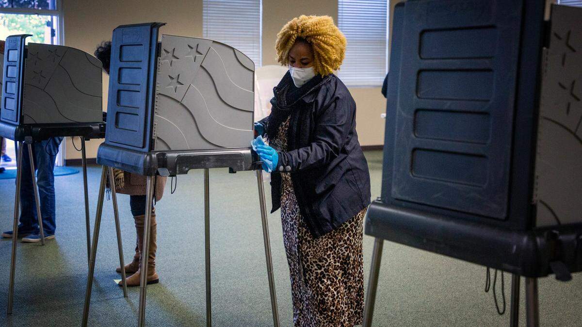 Gail Clay sanitizes voting booths on Election Day at the Ivy Community Center, on Tuesday, Nov. 3, 2020, in Durham, N.C.