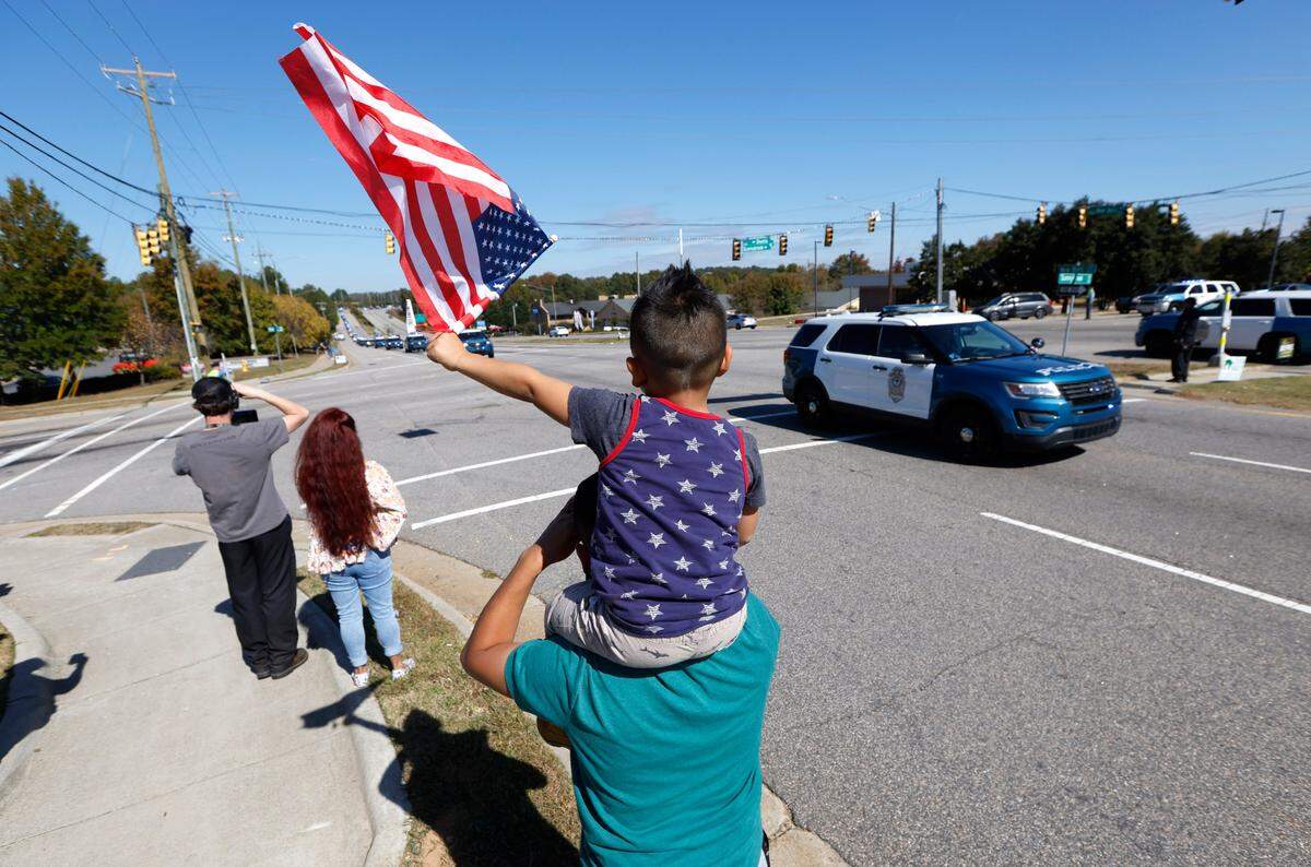Xavier Rodriguez, 5, and his father, Oli, pay their respects as a funeral procession for Raleigh Police Officer Gabriel Torres passes them on New Bern Ave. while on its way to Brown-Wynne funeral home in Raleigh Saturday, Oct. 22, 2022. Officer Torres was killed in a mass shooting Oct. 13