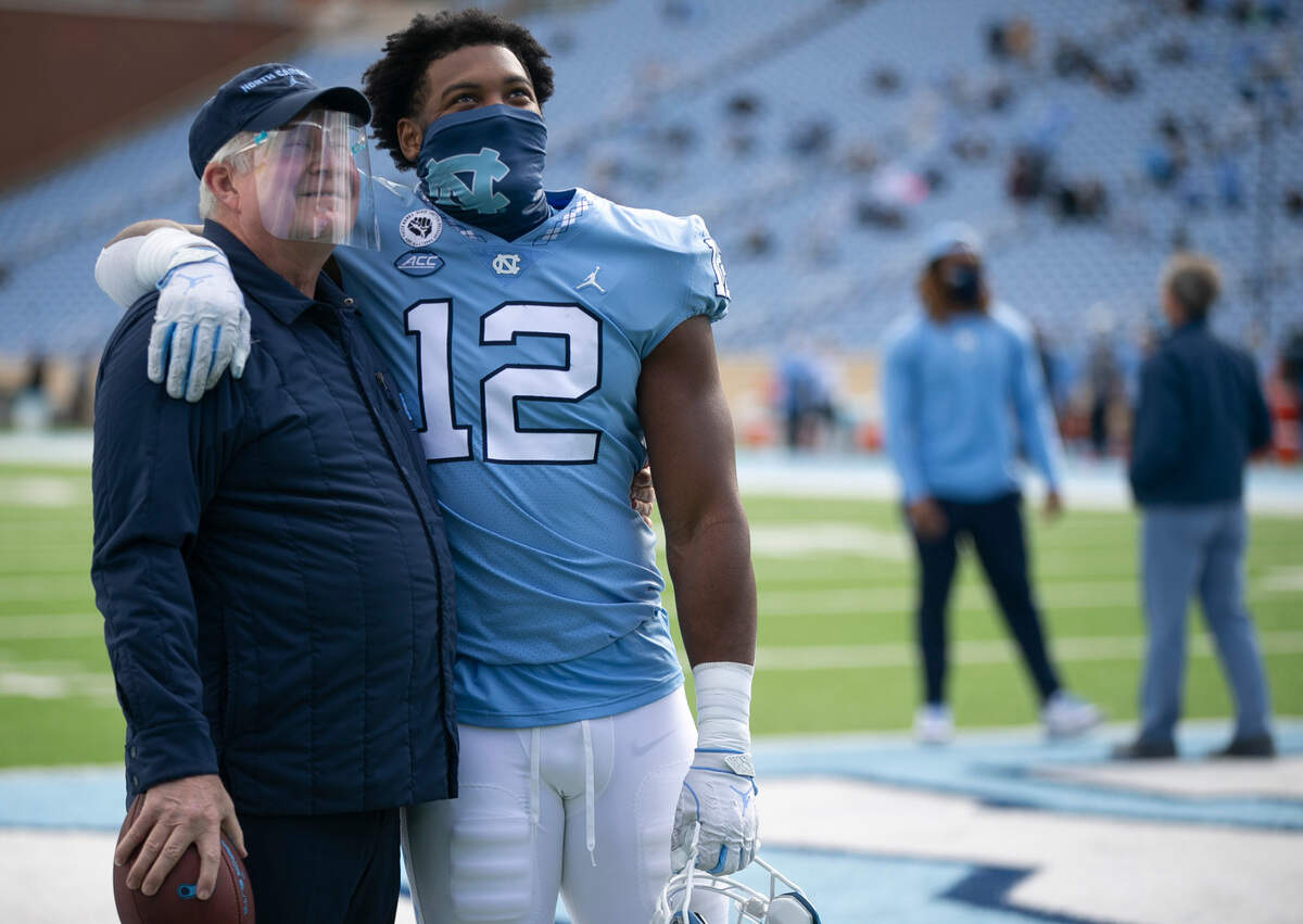 Senior Tomon Fox embraces North Carolina coach Mack Brown as 16 Tar Heel seniors are recognized before playing their final home game in Kenan Stadium on Saturday, December 5, 2020 in Chapel Hill, N.C.