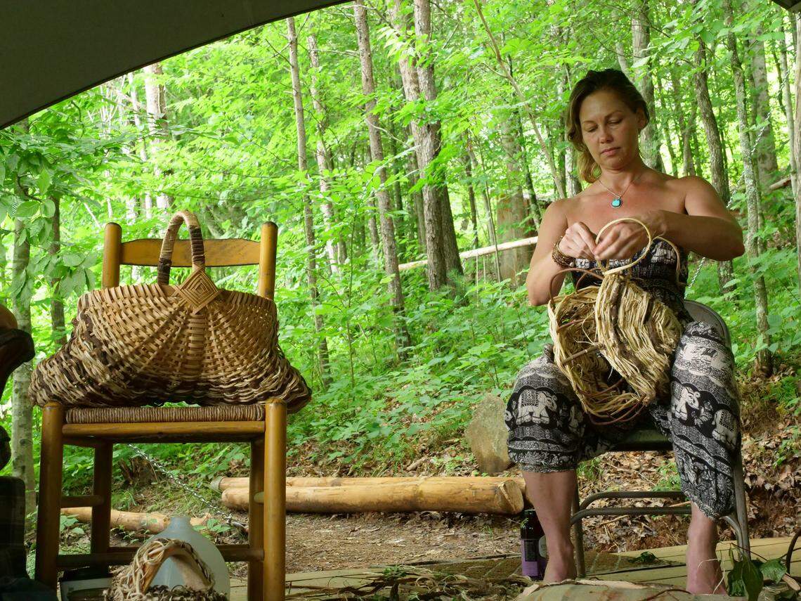 A woman at the Wild Abundance rewilding weekend weaves a kudzu basket.