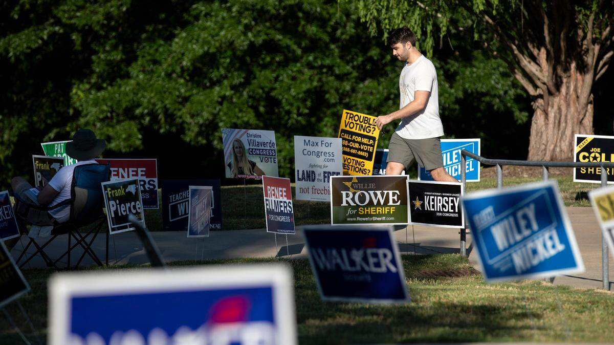 A person walks through campaign signs outside of the John Chavis Memorial Park Community Center polling site on May 17, 2022 in Raleigh.