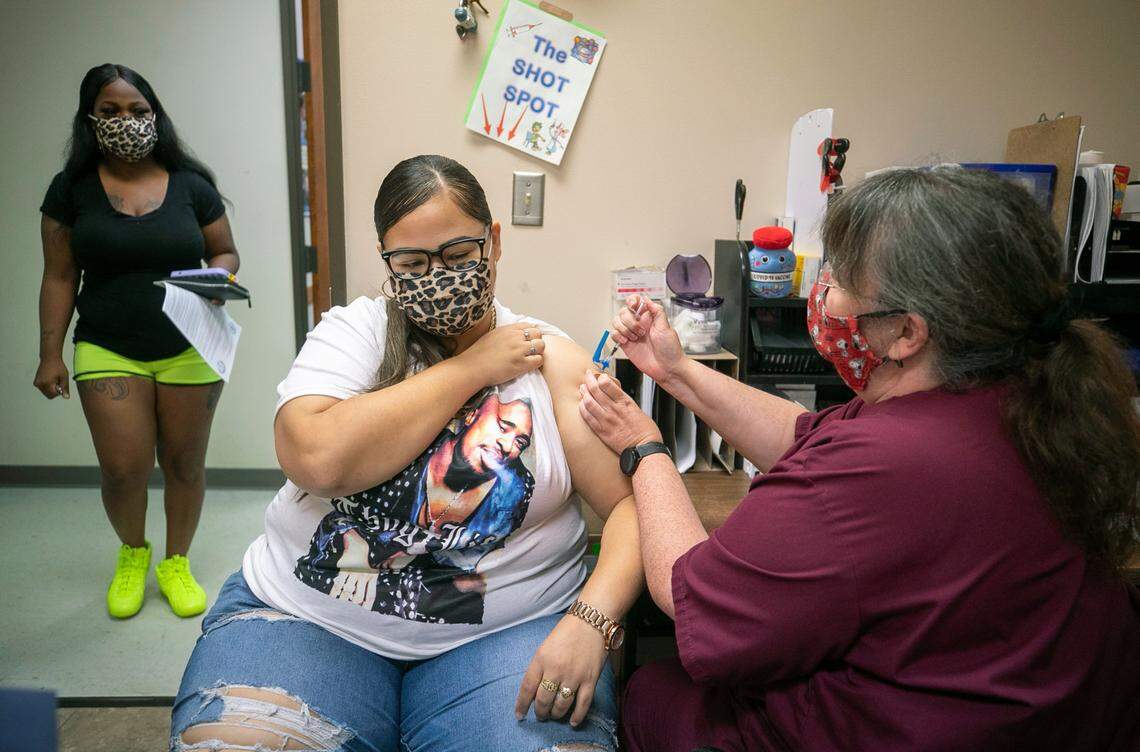 Sheranda Brooks receives her first dose of the Pfizer COVID-19 vaccine at the Robeson County Health Department on Tuesday, August 24, 2021 in Lumberton, N.C. Tamika Montgomery, waits outside for her friend after also receiver her first dose. To date only 34% of the Robeson County population has received one dose of the COVID-19 vaccine.