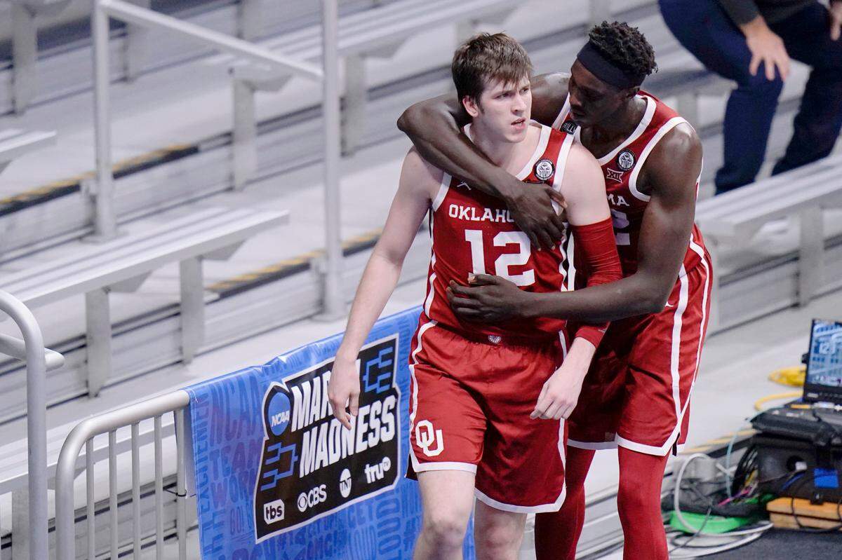Oklahoma guard Austin Reaves (12) reacts to committing a foul and is hugged by teammate Kur Kuath while playing Gonzaga in the second half of a college basketball game in the second round of the NCAA tournament at Hinkle Fieldhouse in Indianapolis, Monday, March 22, 2021. 