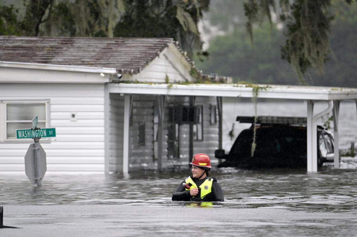 A first responder with Orange County Fire Rescue makes her way through floodwaters looking for residents of a neighborhood needing help in the aftermath of Hurricane Ian, Thursday, Sept. 29, 2022, in Orlando, Fla. Climate change added at least 10% more rain to Hurricane Ian, a study prepared immediately after the storm shows.