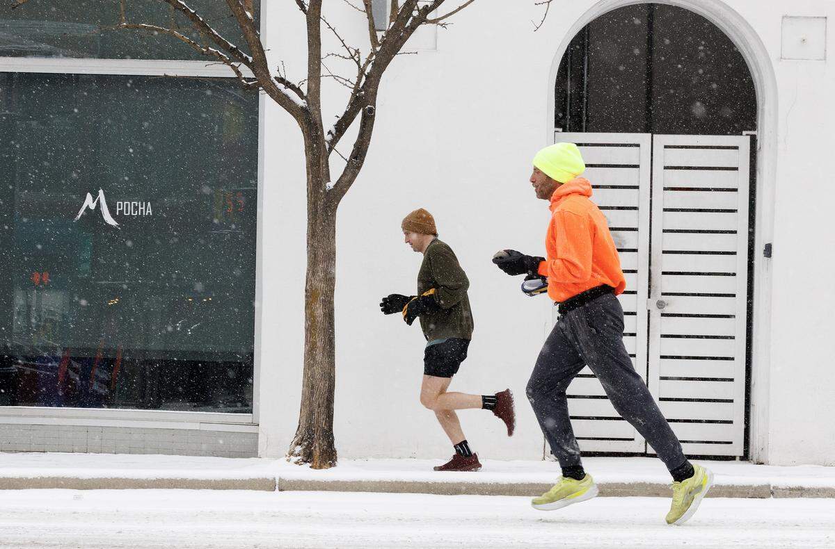 People run along Chapel Hill Street as snow falls on Saturday, Jan. 31, 2026, in downtown Durham, N.C.