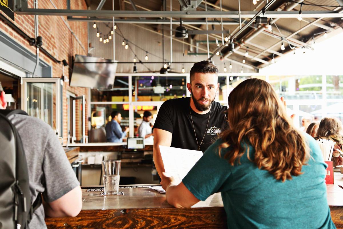 Jacob Lishen, a bartender at The Arbor, talks with a customer in the outdoor bar at Morgan Street Food Hall in downtown Raleigh, Aug. 20, 2018.