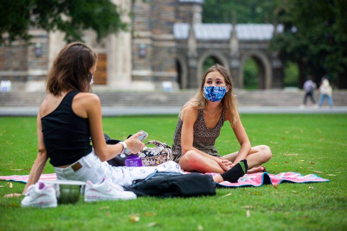 Students Molly Monsour, left, and Madeleine Yancy share a socially-distanced visit with masks to prevent the spread of COVID-19 on the lawn in front of Duke Chapel at Duke University on Tuesday, Sept. 1, 2020, in Durham, N.C.