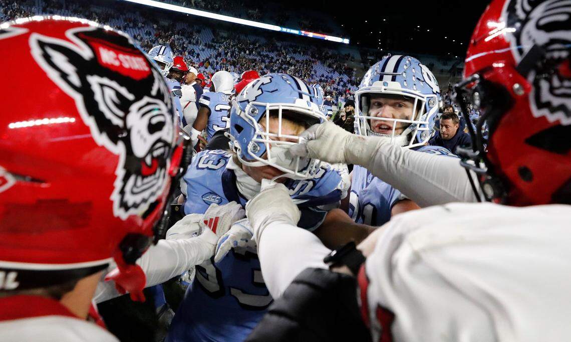 N.C. State players including Anthony Belton (74), right, and North Carolina players, including Gibson Macrae (53) scuffled after N.C. State’s 35-30 victory over UNC at Kenan Stadium in Chapel Hill, N.C., Saturday, Nov. 30, 2024.