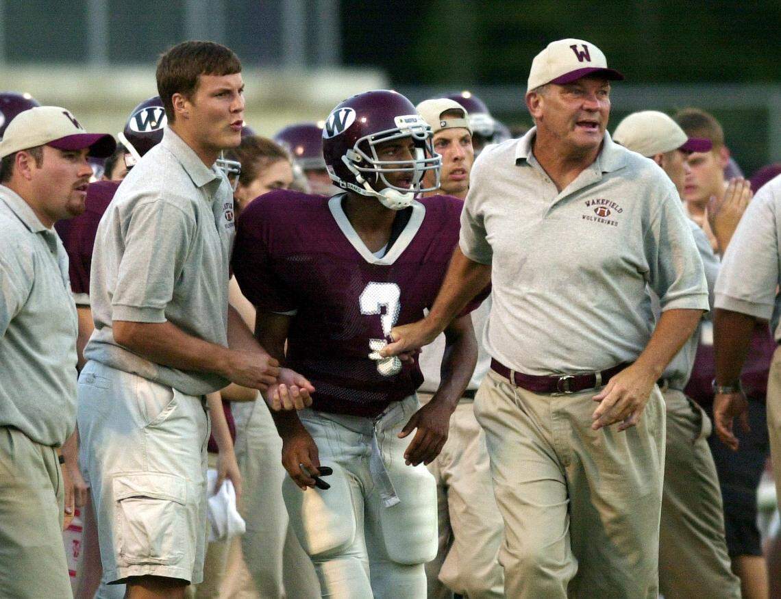 N.C. State quarterback Philip River helps his father, Wakefield coach Steve Rivers, right, during the game against Green Hope at Wakefield in August 2001.
