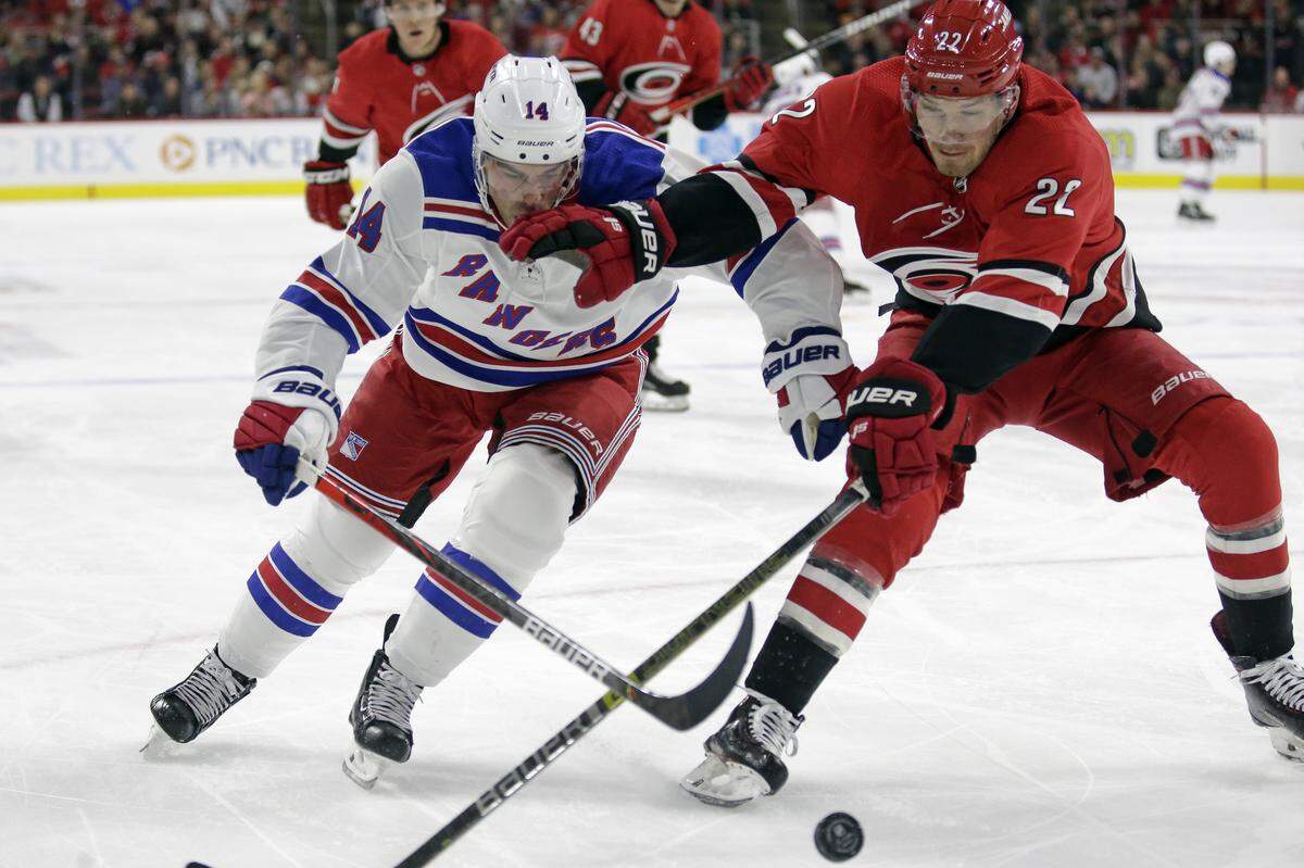 New York Rangers center Greg McKegg (14) and Carolina Hurricanes defenseman Brett Pesce (22) skate to the puck during the first period of an NHL hockey game in Raleigh, N.C., Thursday, Nov. 7, 2019.