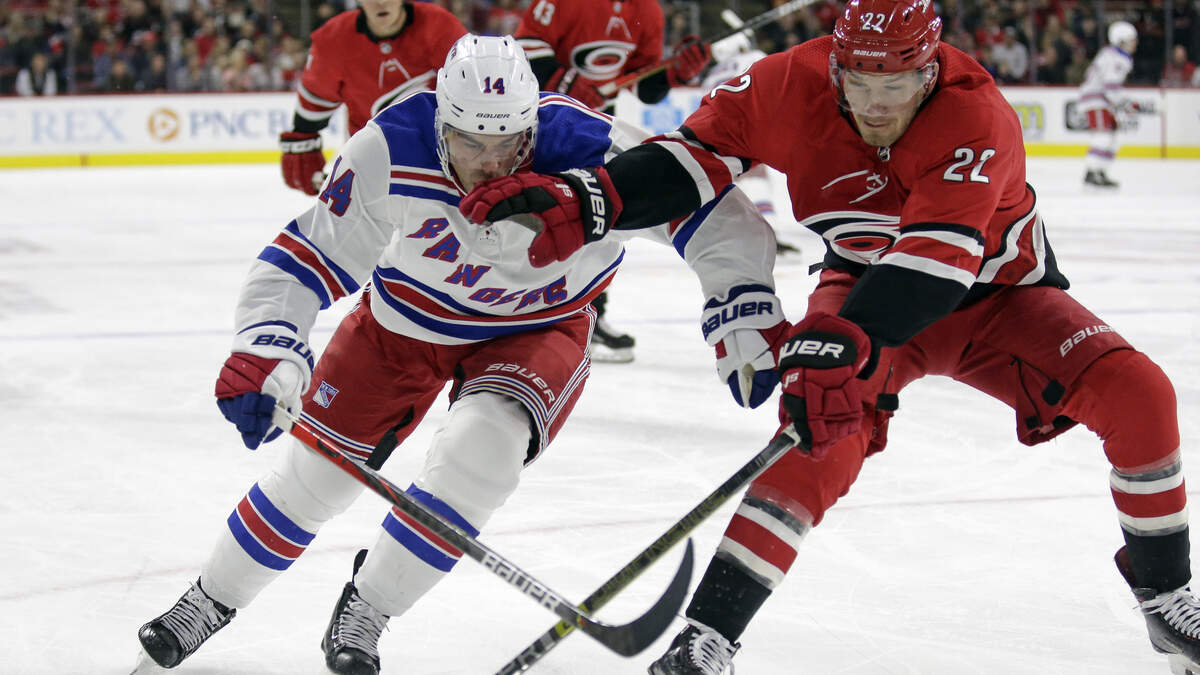 New York Rangers center Greg McKegg (14) and Carolina Hurricanes defenseman Brett Pesce (22) skate to the puck during the first period of an NHL hockey game in Raleigh, N.C., Thursday, Nov. 7, 2019.