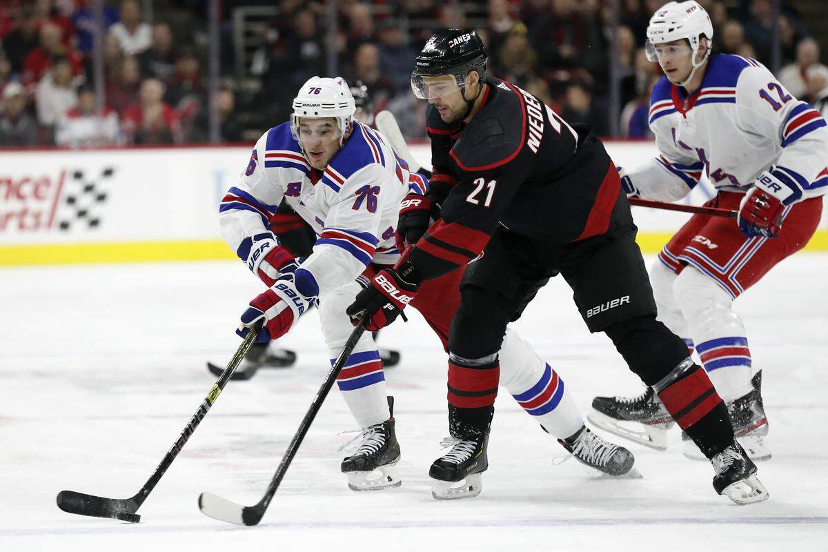 New York Rangers defenseman Brady Skjei (76) and Carolina Hurricanes right wing Nino Niederreiter (21) chase the puck during the first period of an NHL hockey game in Raleigh, N.C., Friday, Feb. 21, 2020. (AP Photo/Gerry Broome)