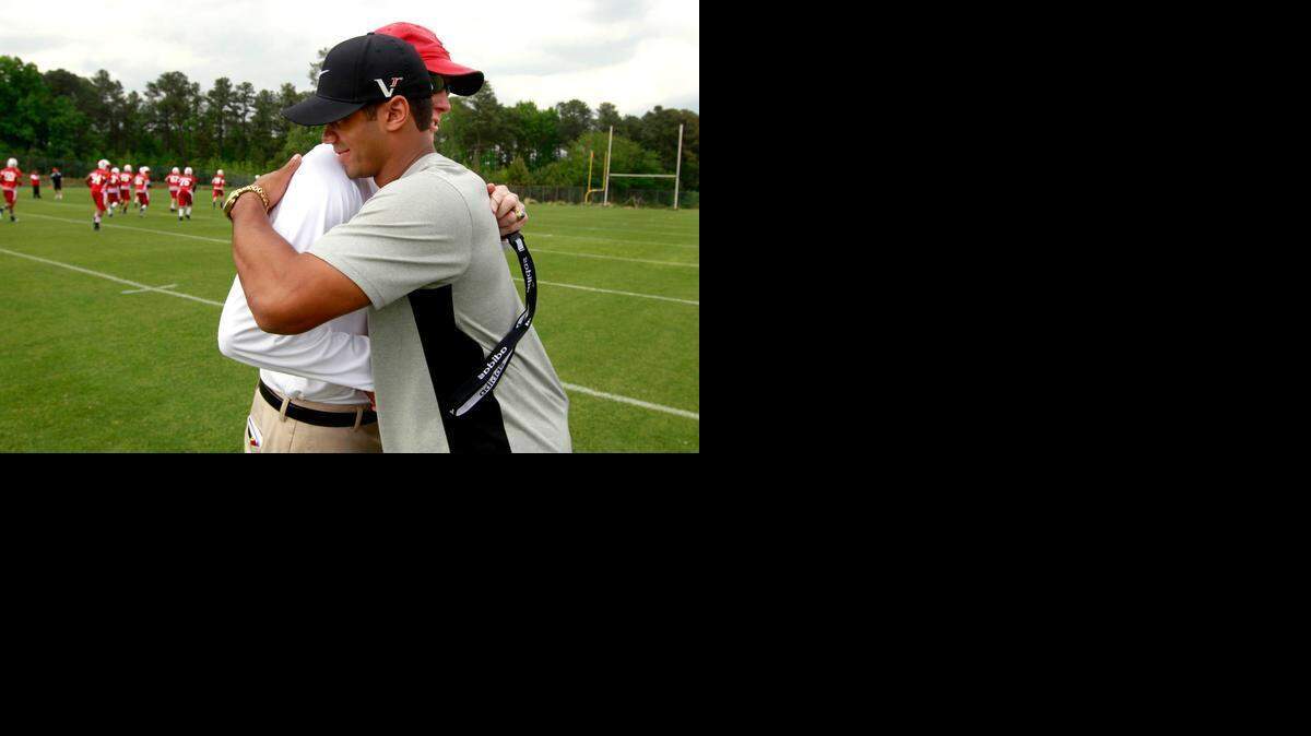 Former Wolfpack quarterback Russell Wilson and head coach Tom O'Brien embrace during N.C. State's spring football practice Friday, April 20, 2012. Many former Wolfpack football alumni, including Wilson, who are in town for the annual reunion, attended the practice.
