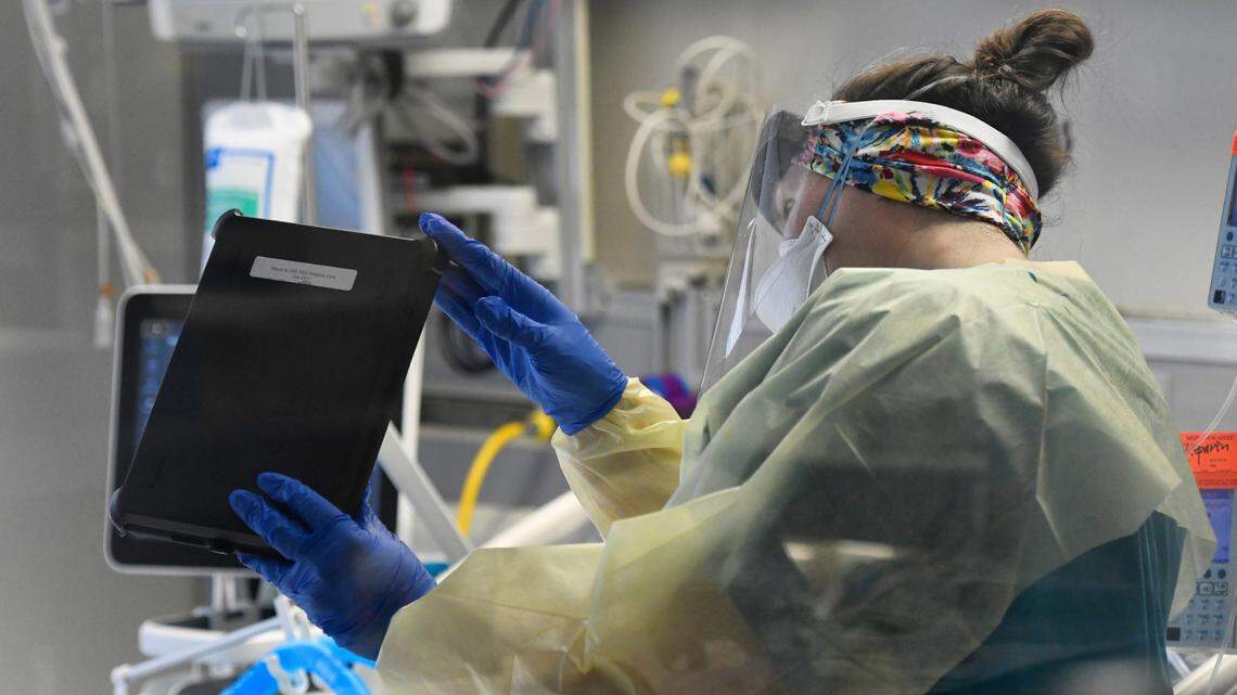 Shannon Costello, a palliative care nurse at UNC Rex Hospital in Raleigh, holds up a tablet so family members can see and talk to a COVID patient in the intensive care unit via a video FaceTime session on March 25, 2021.